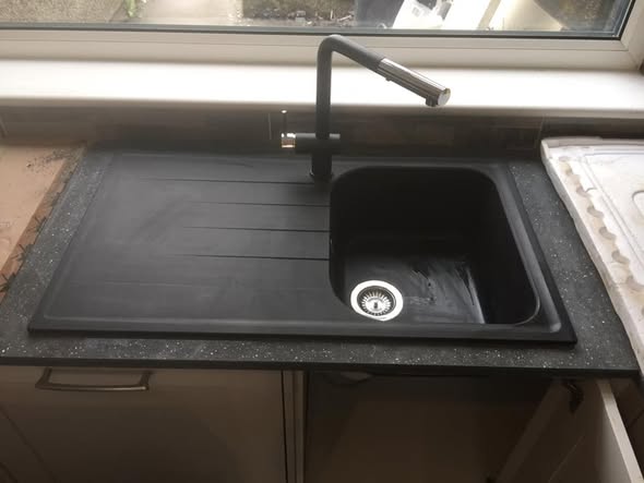 Dark kitchen sink and drainer with a chrome mixer tap